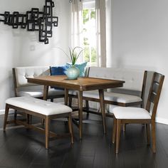 a dining room table with four chairs and a bench in front of the window,