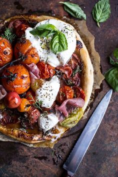 a pizza topped with tomatoes, cheese and herbs