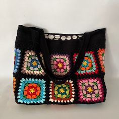 a multicolored crocheted bag is displayed on a white surface