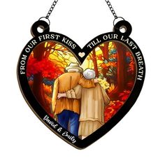 a heart shaped stained glass ornament with an image of two people hugging each other