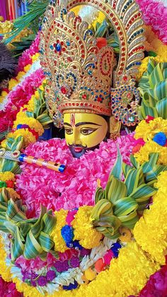 an elaborately decorated mask is displayed in front of other colorful flowers and foliages