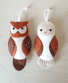 two felt owl ornaments hanging from strings on a table