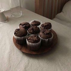 chocolate cupcakes on a wooden plate sitting on a bed