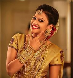 a woman in a gold sari smiles and poses for the camera