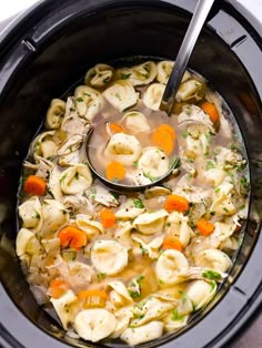 a ladle scooping some soup out of the crock pot filled with tortellini shells