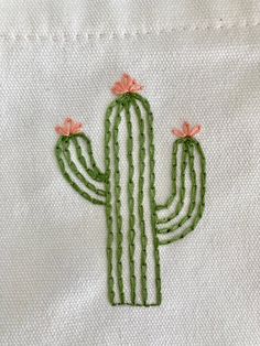 a cactus embroidered onto a white shirt with pink flowers on the back and bottom part