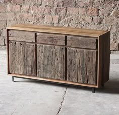 a wooden cabinet sitting on top of a cement floor next to a brick wall in front of a stone wall