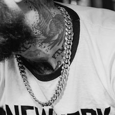 black and white photograph of a man with tattoos on his face wearing a chain around his neck