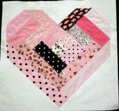 a patchwork heart quilted in pink, black and white polka dot fabric on a piece of cloth