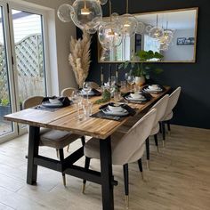 a dining room table is set with place settings and glass orbs hanging from the ceiling