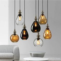 a living room filled with lots of different colored light bulbs hanging from the ceiling over a white table