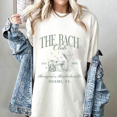 a woman wearing a white t - shirt with the words the beach club on it