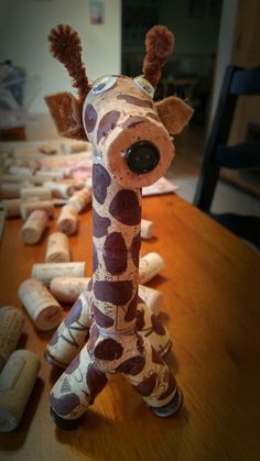 a giraffe made out of wine corks sitting on top of a wooden table