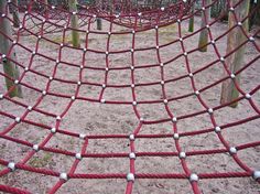 an outdoor playground with red ropes and white balls