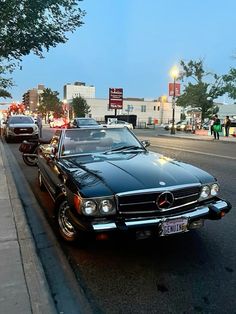 an old mercedes sits parked on the side of the road