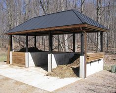 an outdoor shelter with two benches and a trash can next to it in the woods