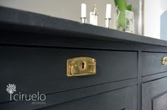 a black dresser with brass handles and knobs on it's doors is shown