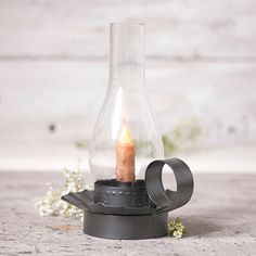 a candle is lit in a glass vase on a stand with metal ring around it