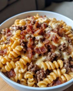 a white bowl filled with pasta and meat covered in cheese on top of a wooden table