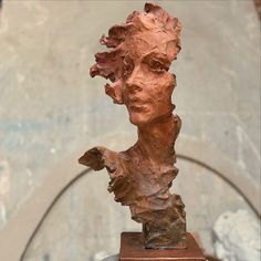 a sculpture of a woman's head on top of a wooden stand