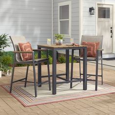 two chairs and a table on a patio with a potted plant in the background