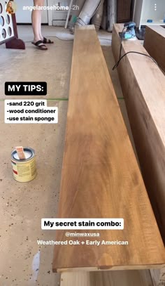 a wooden bench sitting in the middle of a room next to a can of paint