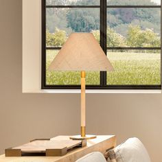 a lamp sitting on top of a wooden table next to a window in a living room