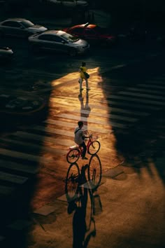 a person riding a bike down a street next to a cross walk and parked cars