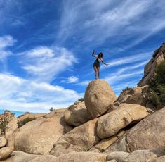 a woman standing on top of a large rock in the middle of a rocky area