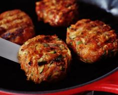 four hamburger patties being cooked in a frying pan with a knife on the side