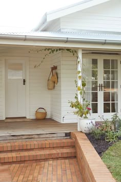 a white house with brick steps leading up to the front door and entryway area