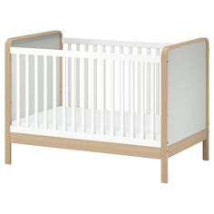 a white crib with wood trim on the bottom and side rails, in front of a white background