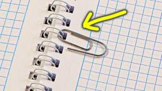 an open notebook with paper clips on it and a yellow arrow pointing to the left