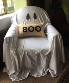 a ghost chair with a boo pillow on it's back in front of a window