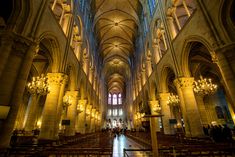 the inside of a cathedral with pews and chandeliers on either side of the navel