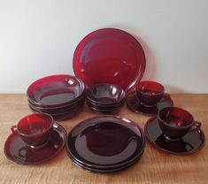 a group of red dishes sitting on top of a wooden table