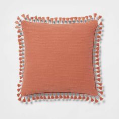 an orange pillow with tassels on it