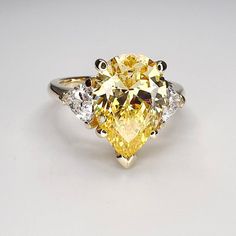 "This ring is a pear shape canary yellow simulated diamond with trillion accents made with solid 14k white gold item #5402 -Approximate total carat weight:  4.80ctw diamond equivalent  -Center Stone Size: 13x9mm  approx. 4.00ct diamond equivalent -Gem Type:  simulated diamond -Stone Shape:  pear shape  -Stone Clarity: VVS1 -Stone Color: canary yellow -Moh's Scale:  8.5 Hardness -Accent Stones: 2 trillions  -Stone size: 5x5mm approx 0.40ct each diamond equivalent -Gem Type:  simulated diamond -Me Yellow Pear Diamond Engagement Ring, Oval Yellow Diamond Promise Ring, Yellow Diamond Solitaire Jewelry, Yellow Solitaire Diamond Jewelry, Yellow Diamond Rings With Accent Stones, Elegant Yellow Pear-shaped Diamond Ring, Pear-shaped Yellow Jewelry With Diamond Accents, Yellow Rings With Diamond Accents For Promise, Yellow Pear-shaped Jewelry With Diamond Accents