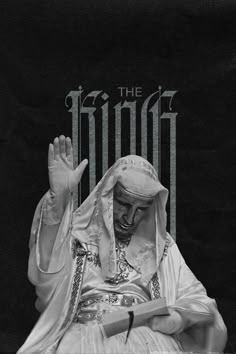 a black and white photo of a nun holding her hands up in the air while sitting on a chair