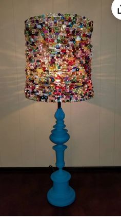 a lamp made out of buttons on a blue base with a light shade over it