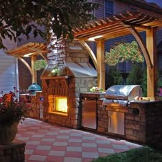 an outdoor bbq grill is lit up at night with the lights on and flowers in front