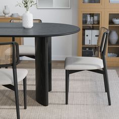 a dining room table with two chairs and a vase on top of it in front of a bookcase