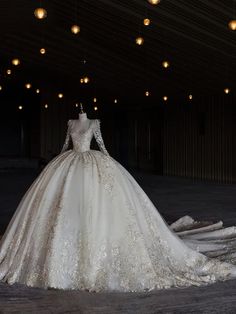 a white wedding dress on display in a dark room with lights hanging from the ceiling