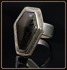 This beautiful gothic coffin design ring has a unique type of tile material that has little chips of shiny black glass encased in a semi-flat binder to create a durable and dynamic looking cabochon. Hand crafted and made to order, these wonderful rings can be customized. Just send us a message and we can work out the details to create a personal, one-of-a-kind piece of jewelry for you. All of our jewelry is completely hand fabricated in-house so we can build it to your specifications. Unique Black Rectangular Jewelry, Black Jewelry With Custom Hardware As Gift, Custom Black Jewelry With Hardware For Gift, Coffin Design, Gothic Coffin, Wedding Ring Finger, Tile Material, Coffin Ring, Blue Goldstone