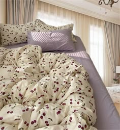 an unmade bed with cherry print on it