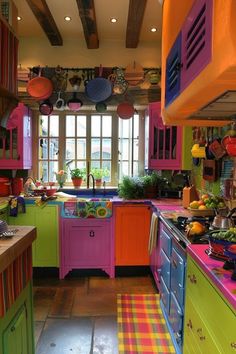 colorful kitchen with lots of pots and pans hanging from the ceiling