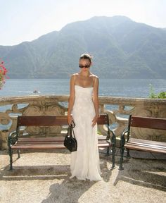 a woman in a white dress standing next to a bench