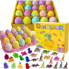 an assortment of dinosaur eggs in a yellow box with dinosaurs and other toys around it