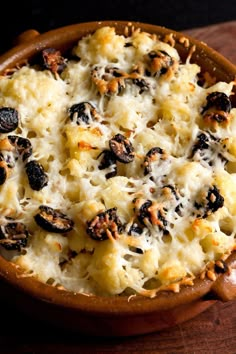 a casserole dish with cheese and raisins in a brown bowl on a wooden table