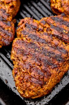 three hamburger patties are cooking on a grill